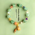 Close-up of a women's jade bracelet with hand-carved orchid-shaped beads on a wrist.