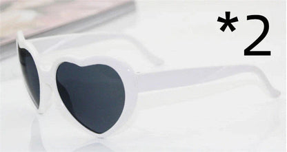 Heart-shaped glow-in-the-dark sunglasses in various vibrant colors, featuring a durable plastic frame and resin lenses for reliable UV protection.