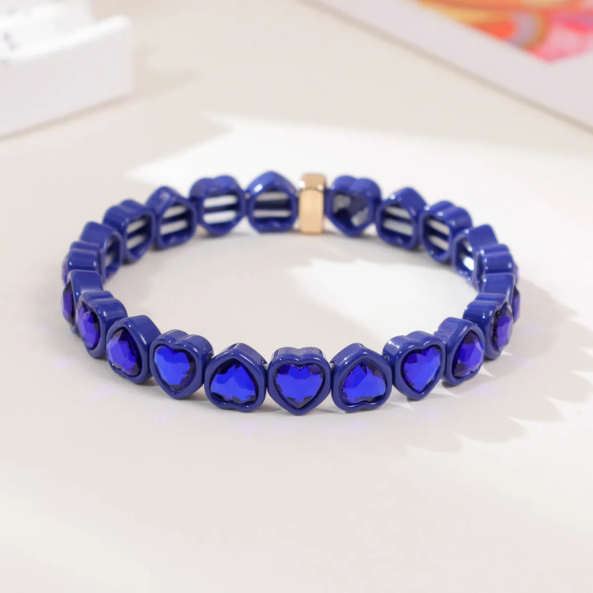Rainbow enamel heart pendant on a stretch alloy bracelet, shown in multiple colour options.