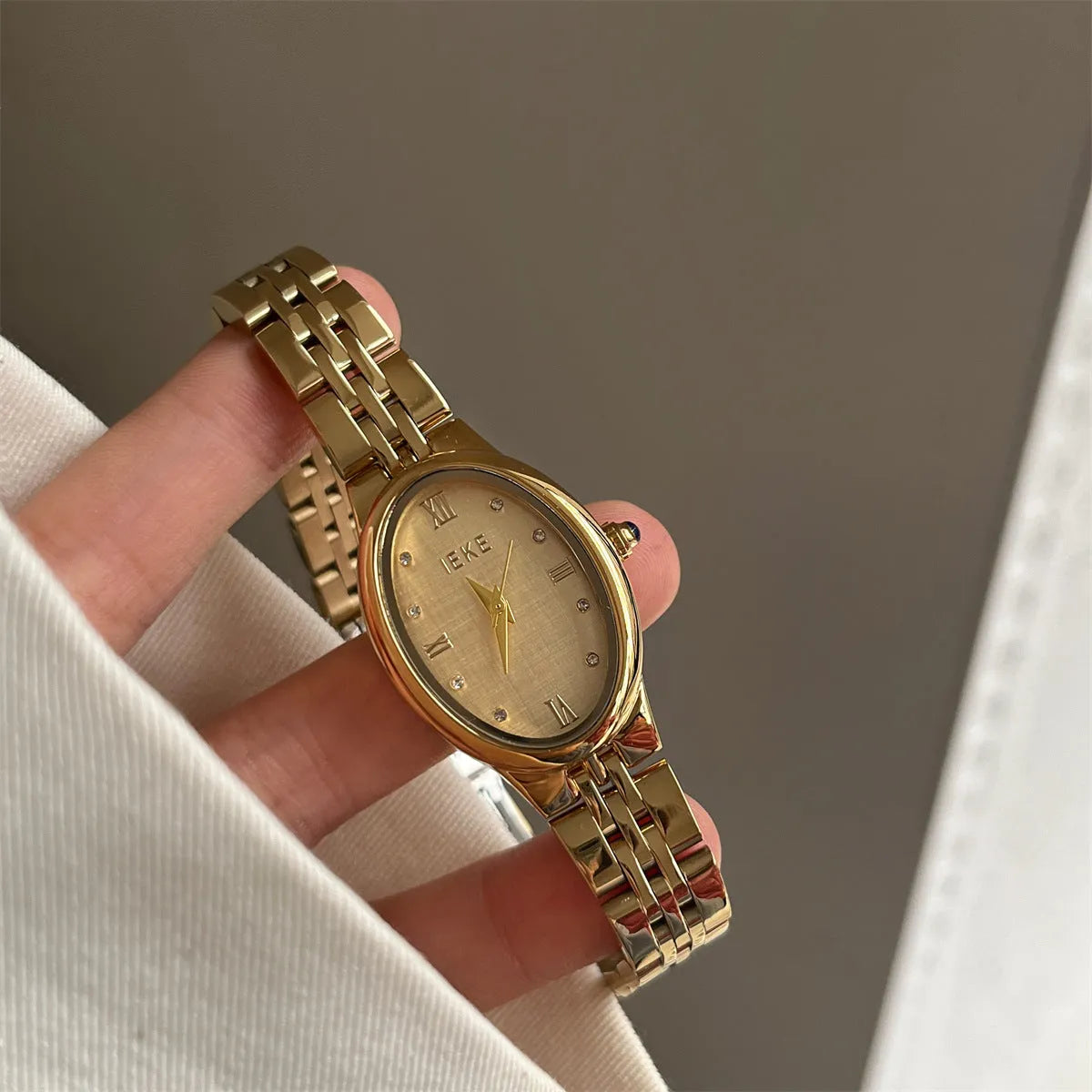Oval dial watch with 37mm case, 10mm thickness, dot markers, and stainless steel butterfly clasp in gold or silver