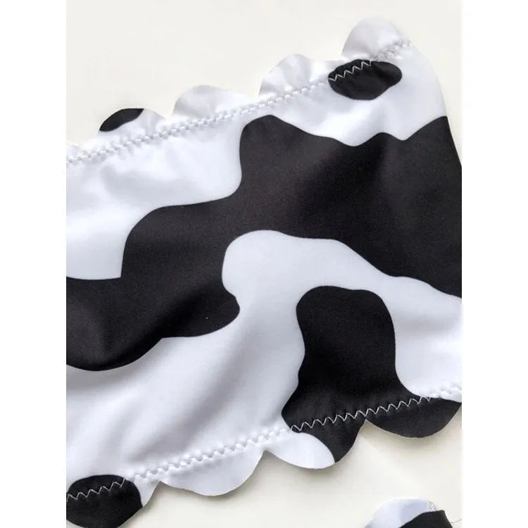 Women's black and white cow print bikini swimsuit with wrapped breast design on display