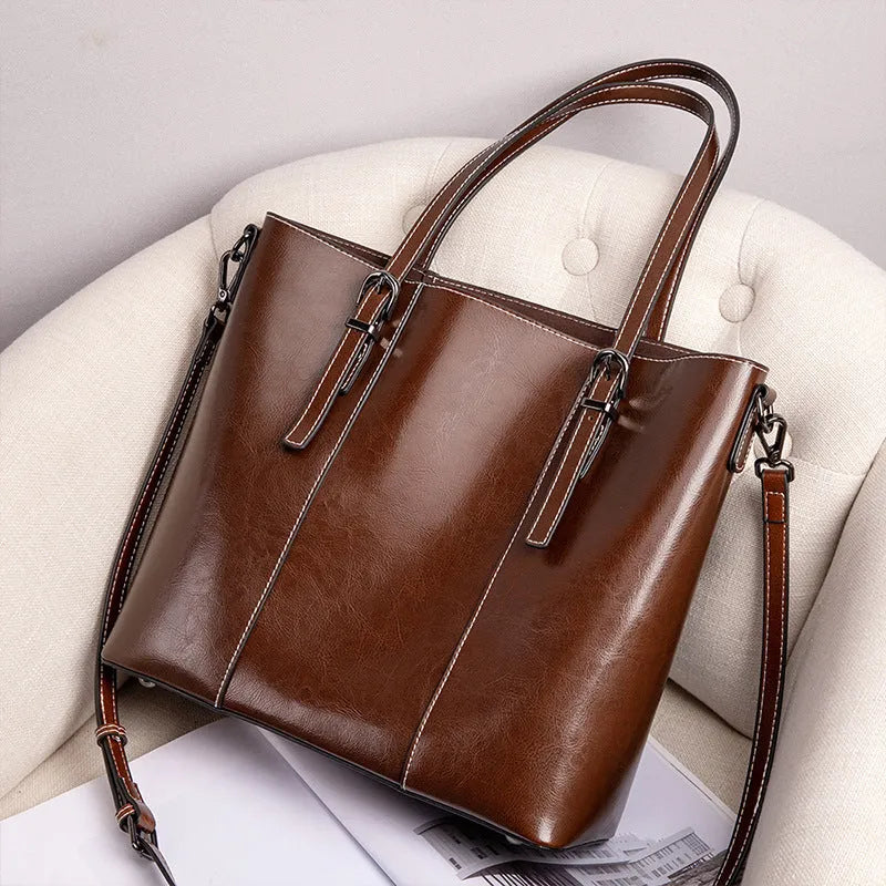 Brown genuine leather retro women's shoulder tote bag with three straps on a table.