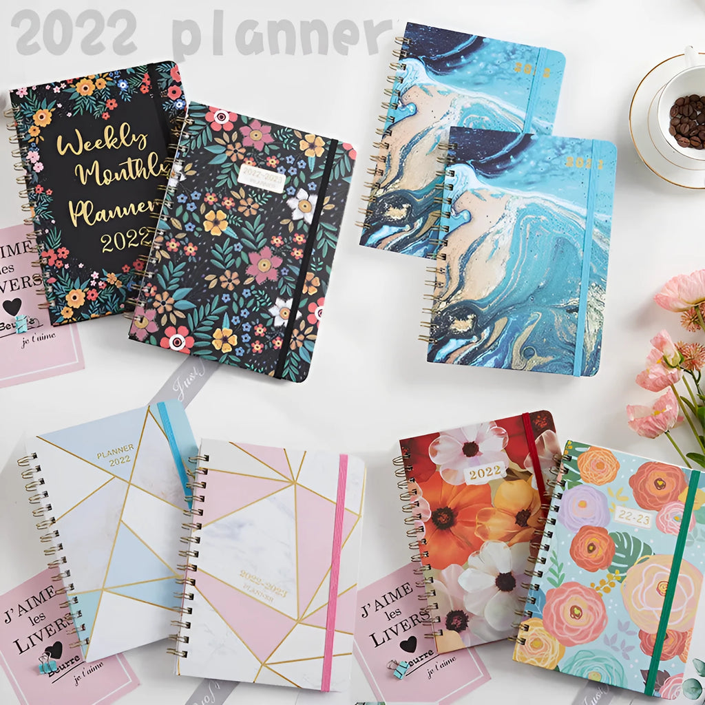 A5 spiral-bound notebook with a colourful floral design cover, lying open on a table.