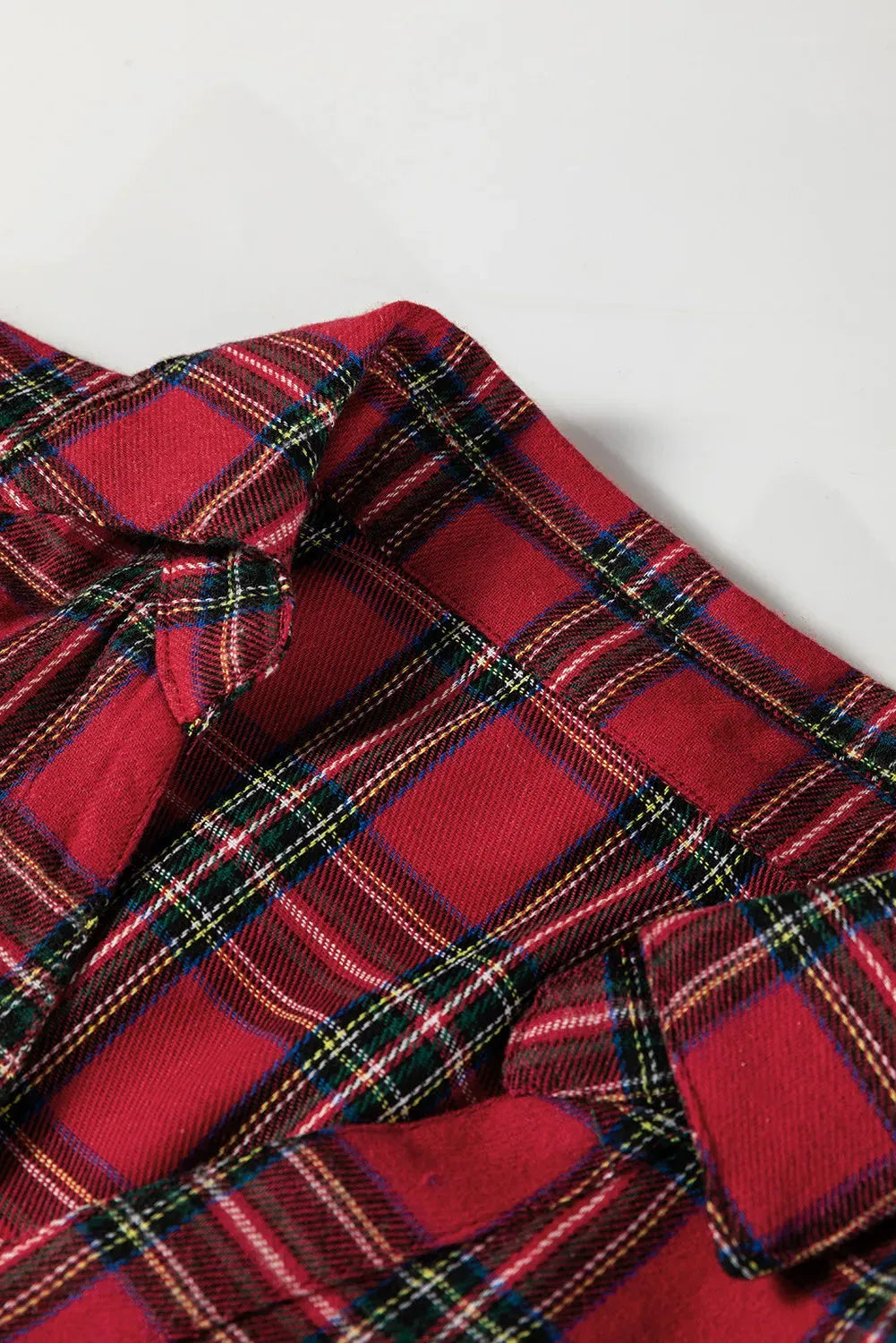 Red plaid women's mini dress with shirt collar, long sleeves, half-button front, and ruffle hem.