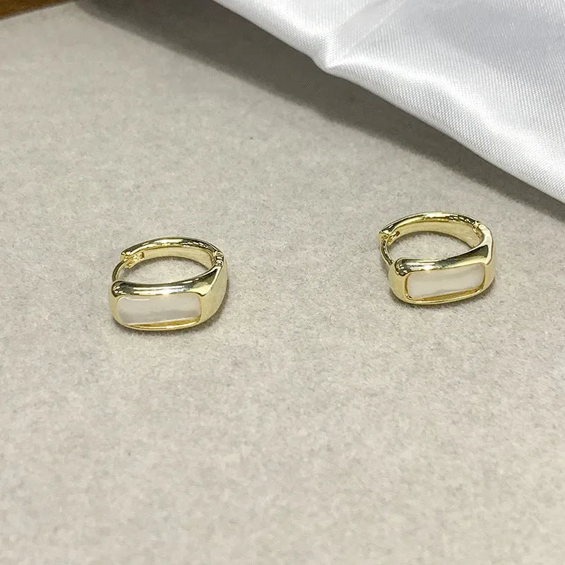 Four pairs of round buckle earrings in gold and silver metal finish on white background
