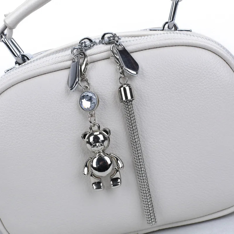 Women's small square stitching bag in oval shape with double shoulder strap showing internal mobile phone compartment.