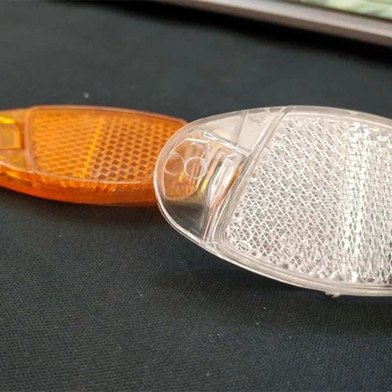 White and yellow plastic bicycle spoke reflectors for front and rear wheel safety.