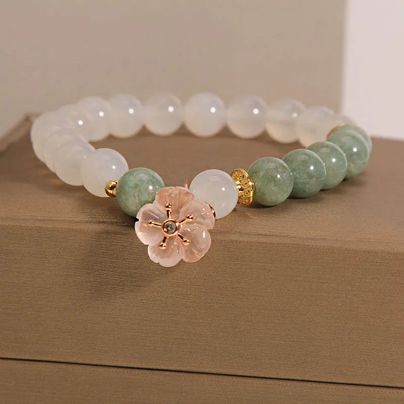 Women's white agate jade bracelet with flower design and pink accents on adjustable sliding knot closure