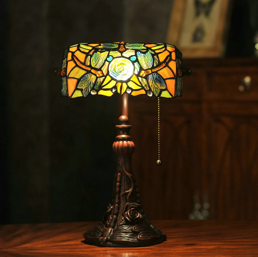 Tiffany stained glass table lamp with coloured lampshade and resin base on a desk