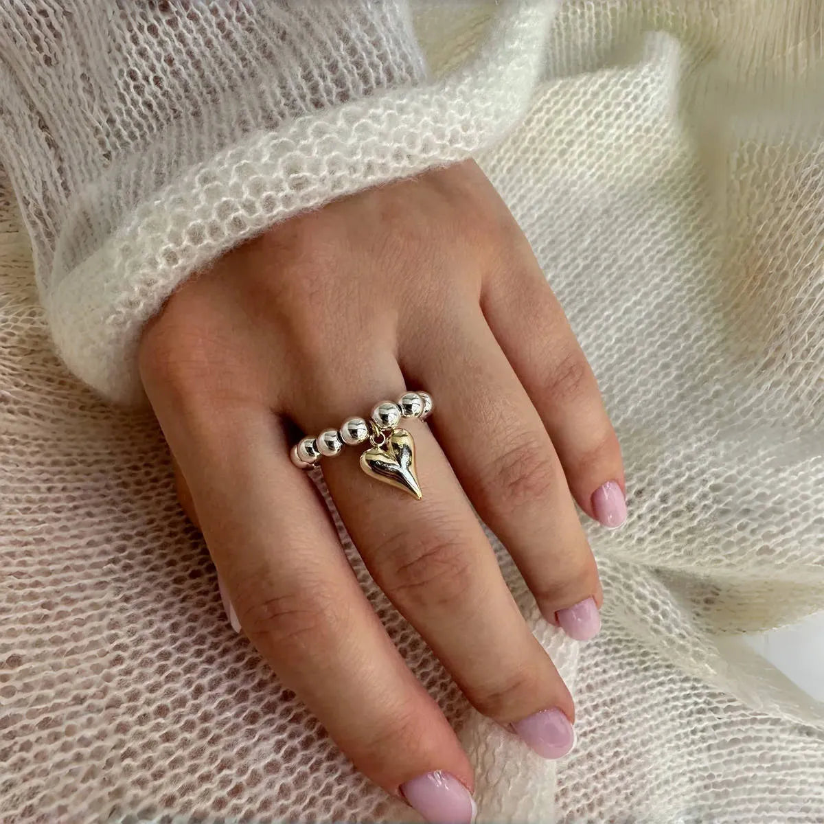 Handmade elastic love ring with geometric beaded string design and heart charm on adjustable band