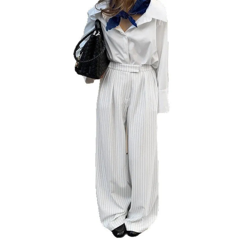 White striped loose-fit wide-leg trousers with a front zipper closure on a model.
