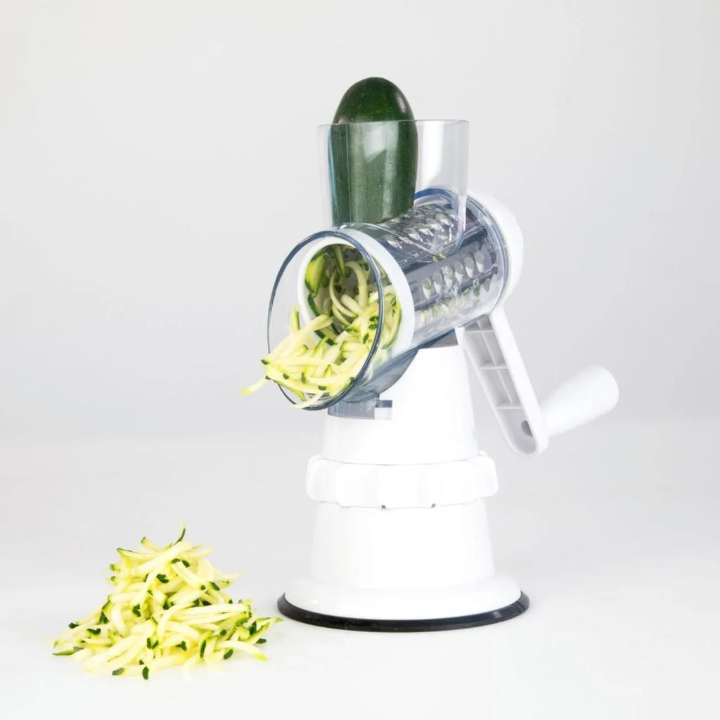 White 3-in-1 manual vegetable slicer and grater with suction feet on a kitchen counter.