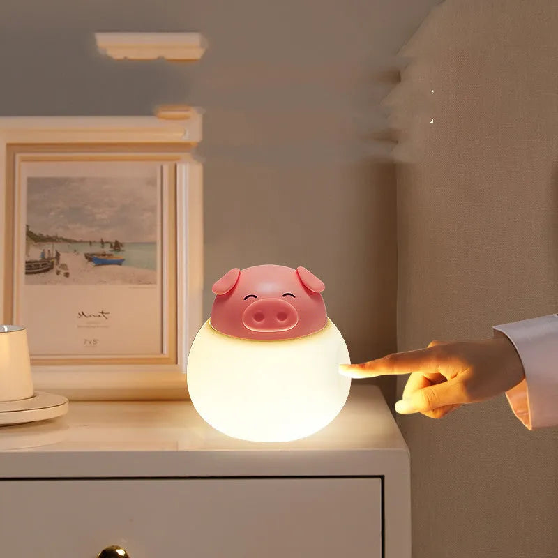 Pink pig silicone pat bedside lamp with USB LED light source on a table