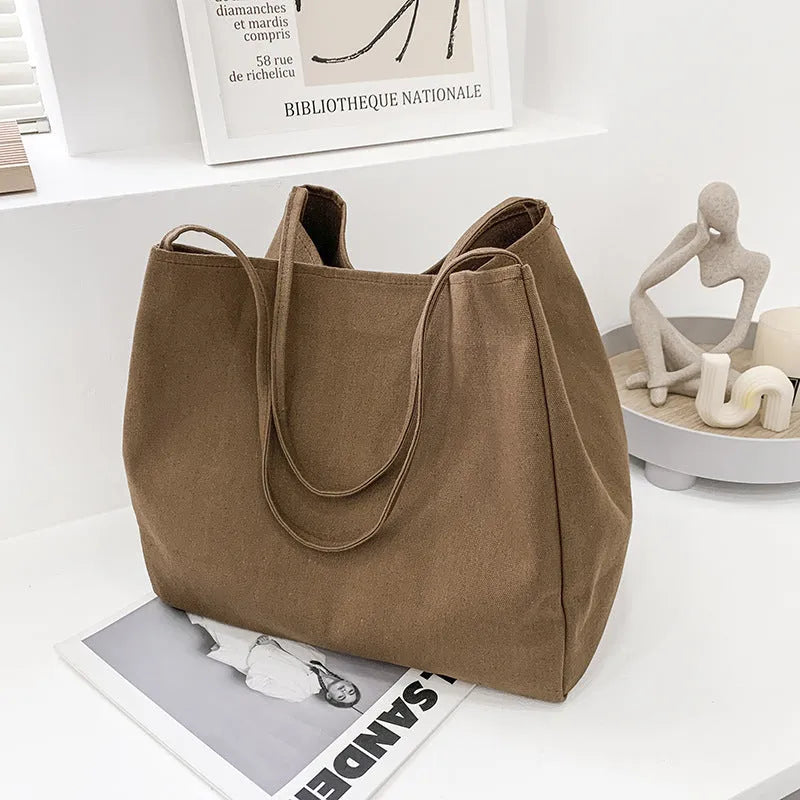 Women's black canvas shopping handbag with double shoulder straps showing internal mobile phone pocket