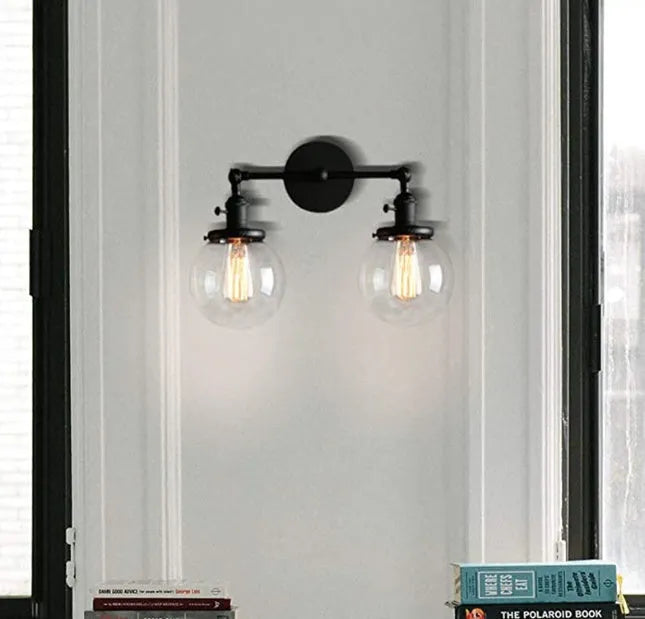 Double headed black iron wall lamp with spherical glass shades on a wall