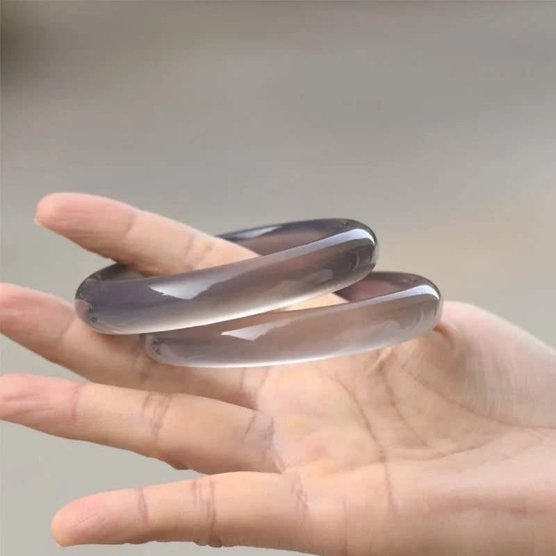 Dark grey iced chalcedony agate bracelet with a continuous circle design on a wrist.