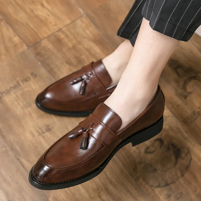 Men's black slip-on business casual shoe with tassel detail and rubber sole.