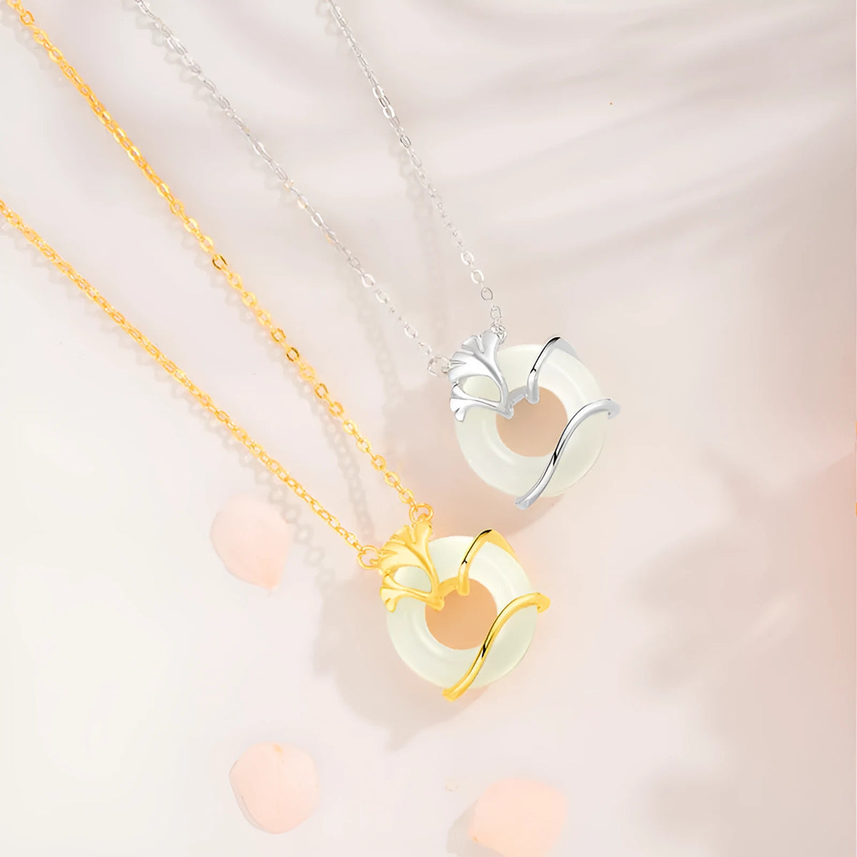 Close-up of a sterling silver peace buckle necklace with a cross chain and ginkgo details, shown in a gold tone.
