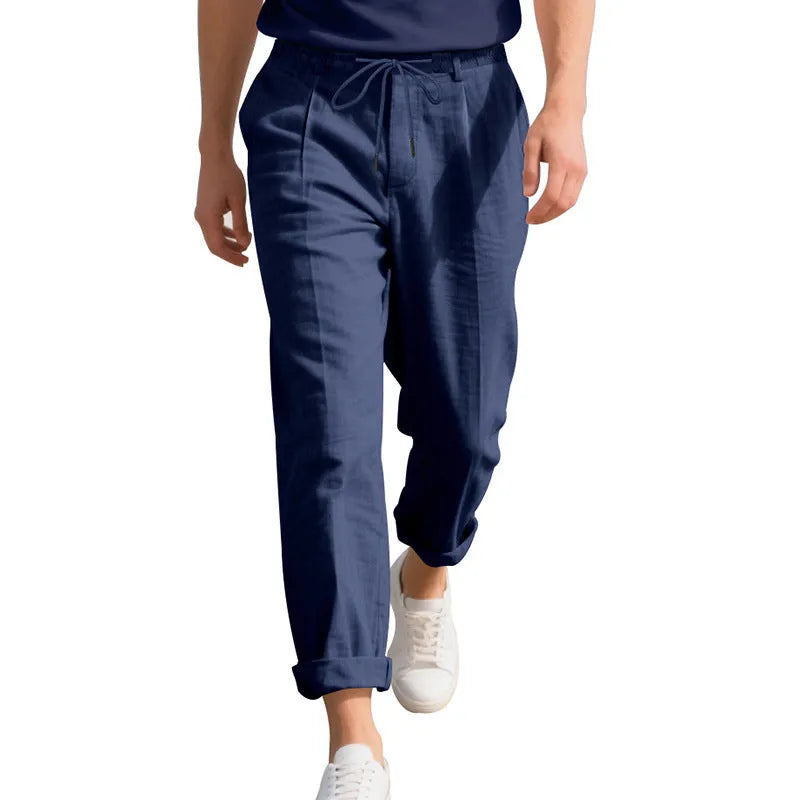 Men's light beige linen trousers with drawstring waist and straight-leg design laid flat