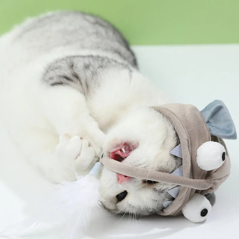 Grey head-mounted cat toy with feather and big-eye fish attachments on adjustable elastic band