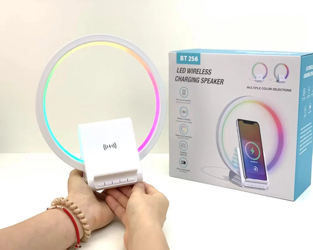 White smart Bluetooth speaker with integrated wireless charging pad and ambience light on a desk.