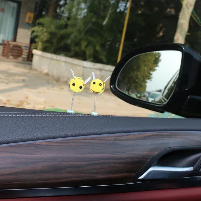 Small black and yellow cartoon bee car decoration with a spring, on a fur ball.