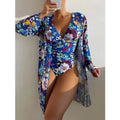 Women's floral print bikini and matching coat three-piece swimsuit set on a hanger.