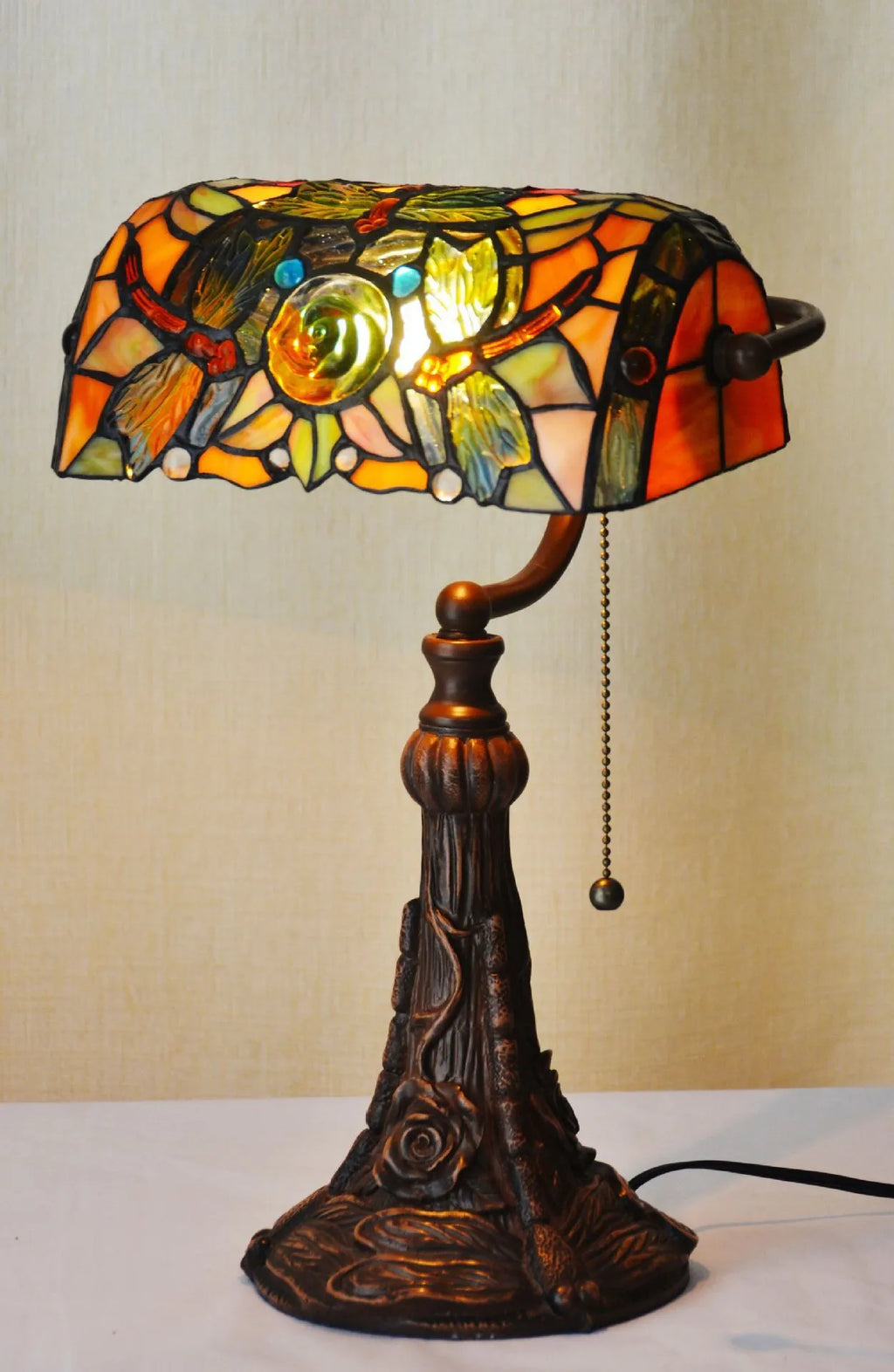 Tiffany stained glass table lamp with coloured lampshade and resin base on a desk