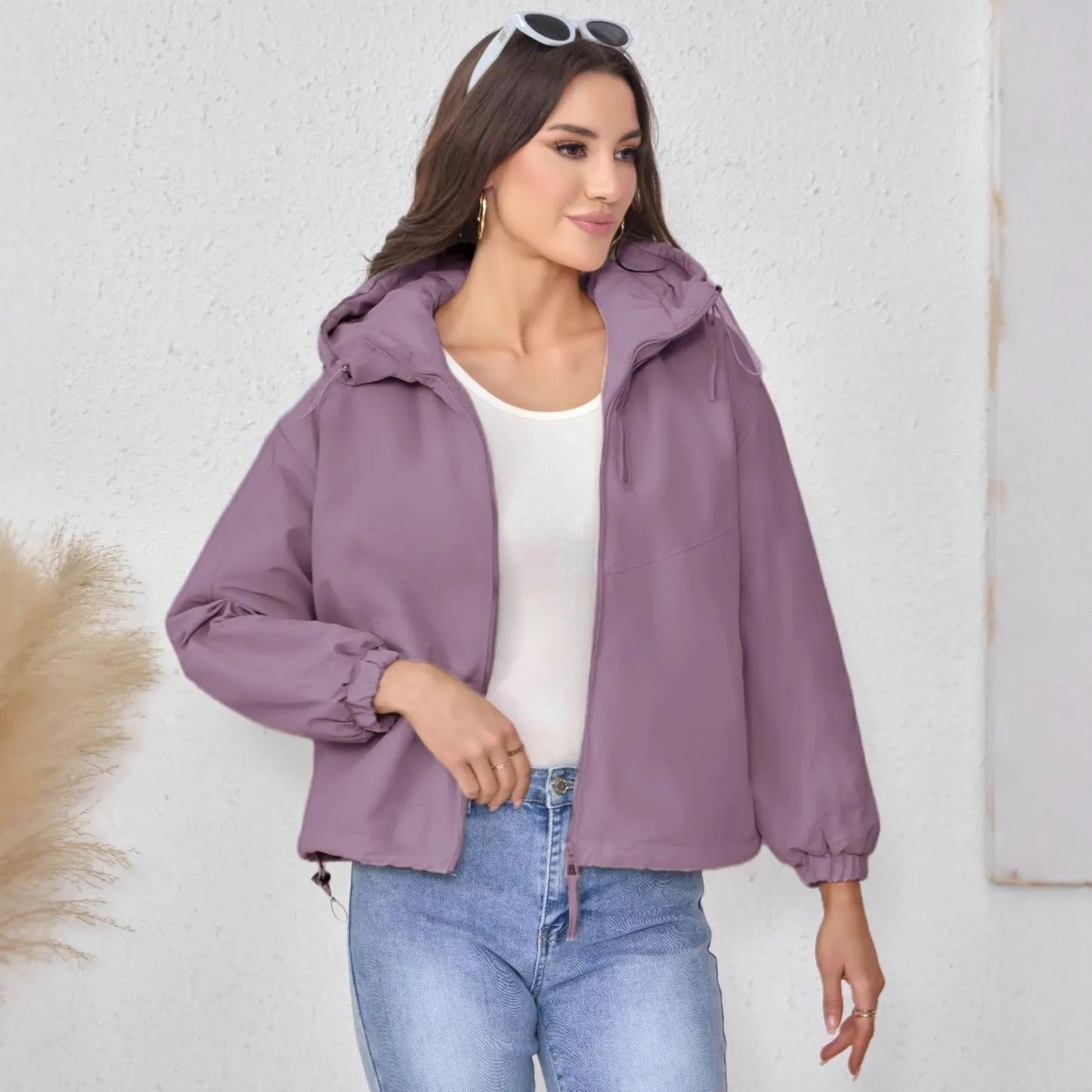 Grey women's loose-fit hooded polyester shell jacket with long sleeves on a hanger.