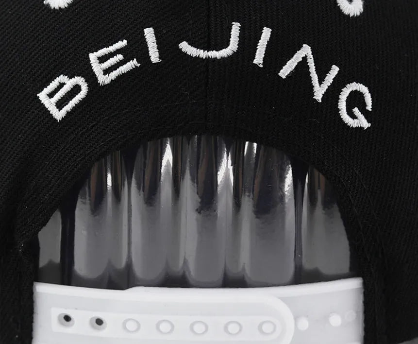 Black and white adjustable cotton baseball cap with embroidered lettering and dome crown.