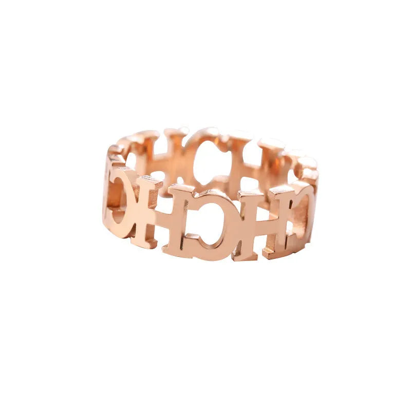 Gold titanium steel hollowed cut letter ring with geometric design on white background