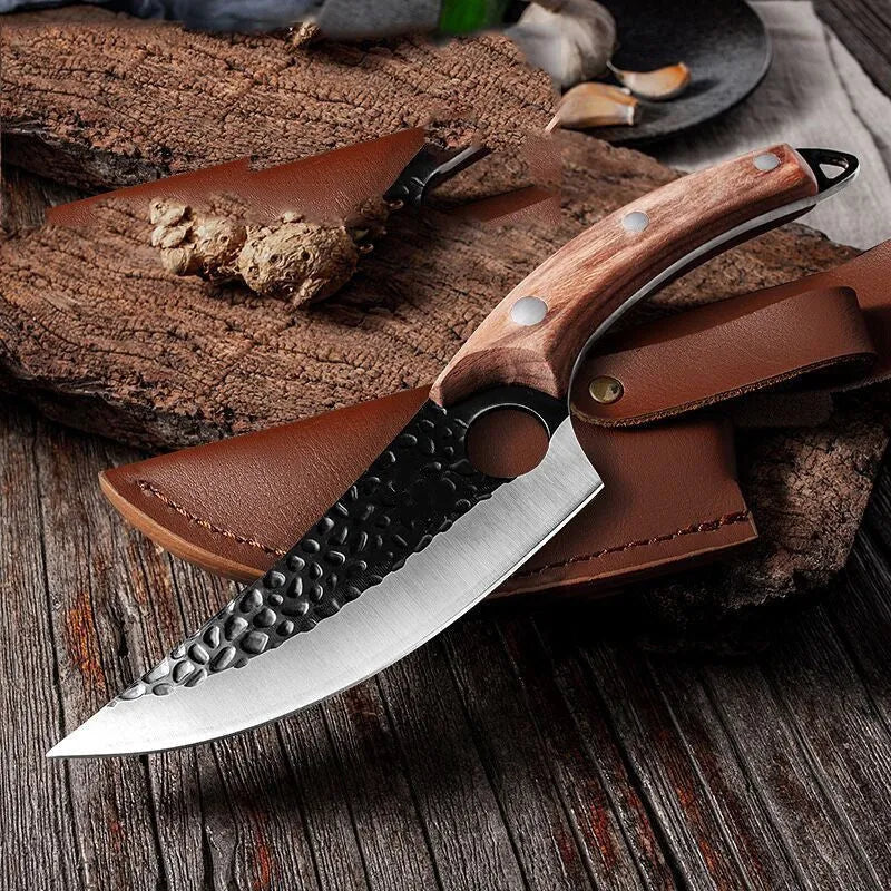 Small scimitar boning knife with hammer pattern finish and black leather sheath on surface