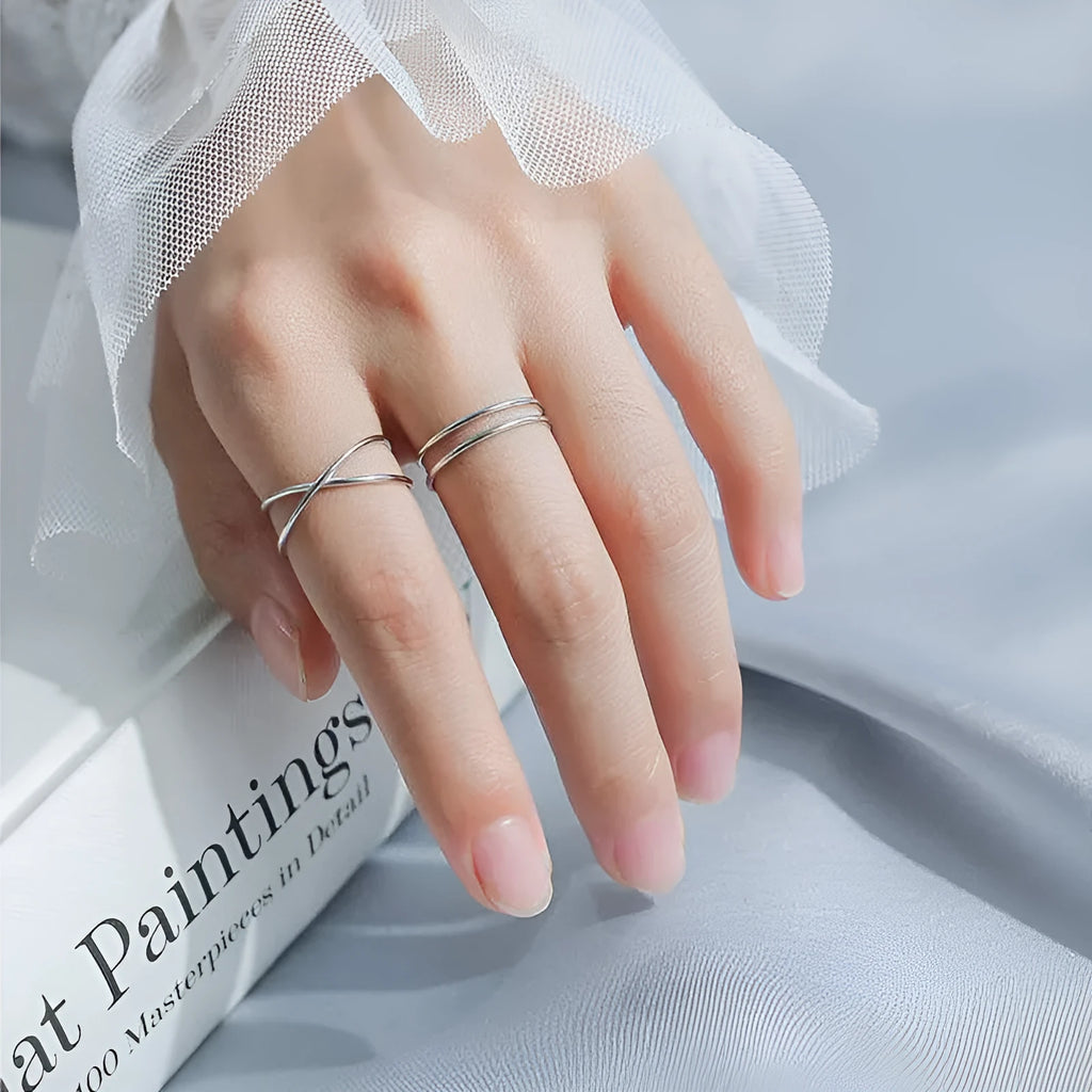 Silver-plated geometric cross ring with an adjustable opening on a copper base.