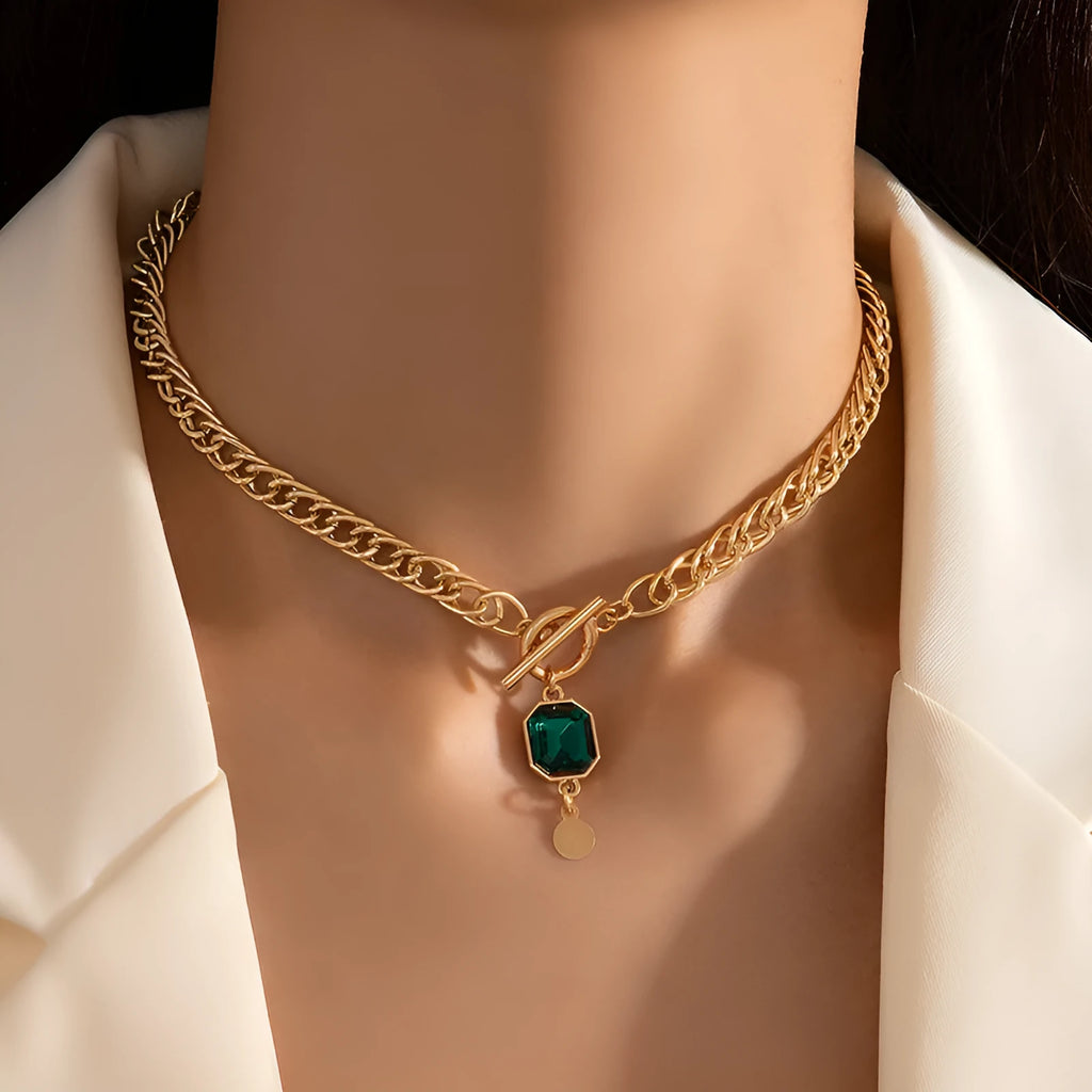 Gold electroplated geometric round pendant necklace with emerald zircon accents on Cuban link chain