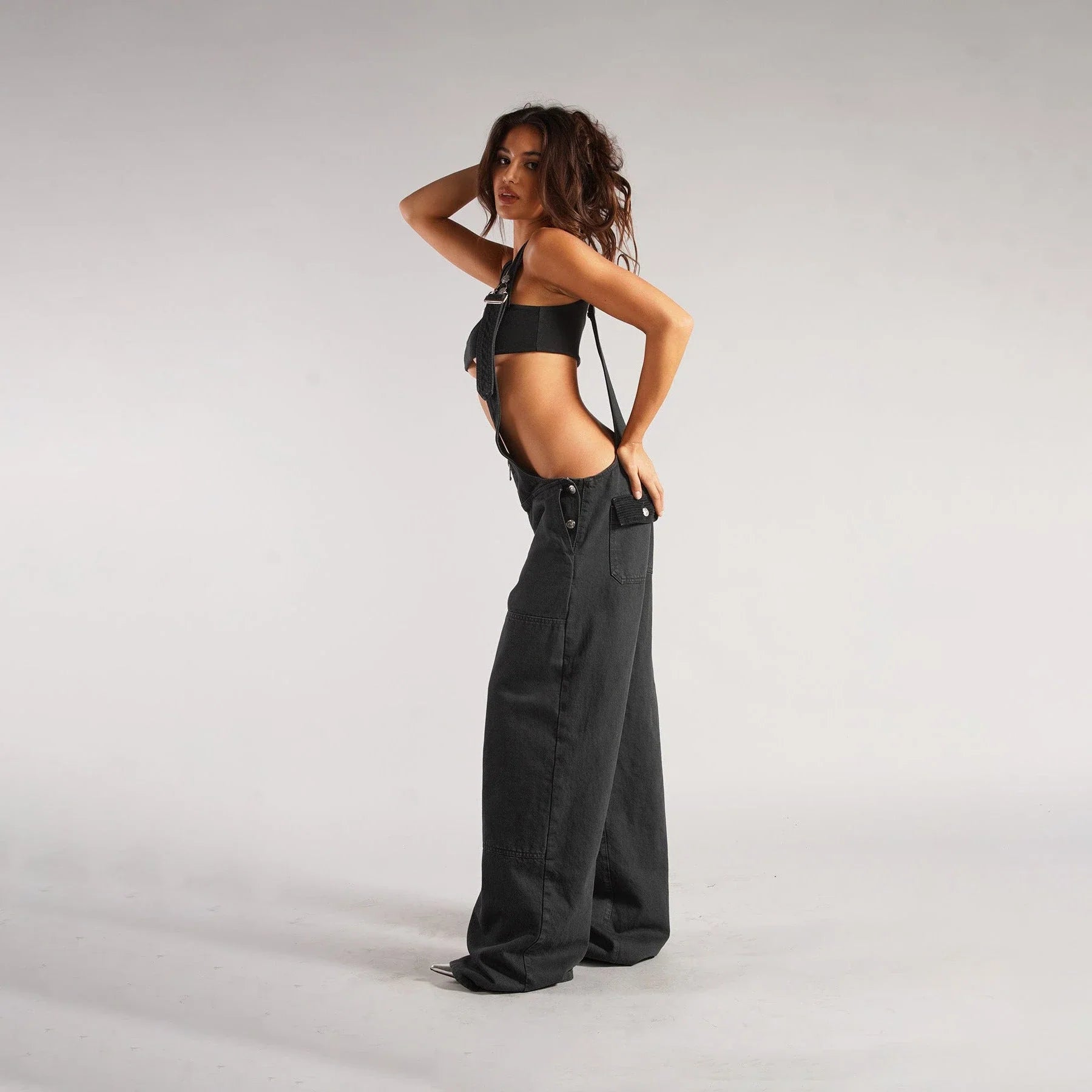 Stylish Y2K-inspired denim suspender jumpsuit with pockets, featuring a relaxed wide-leg silhouette and adjustable straps for a customized fit.