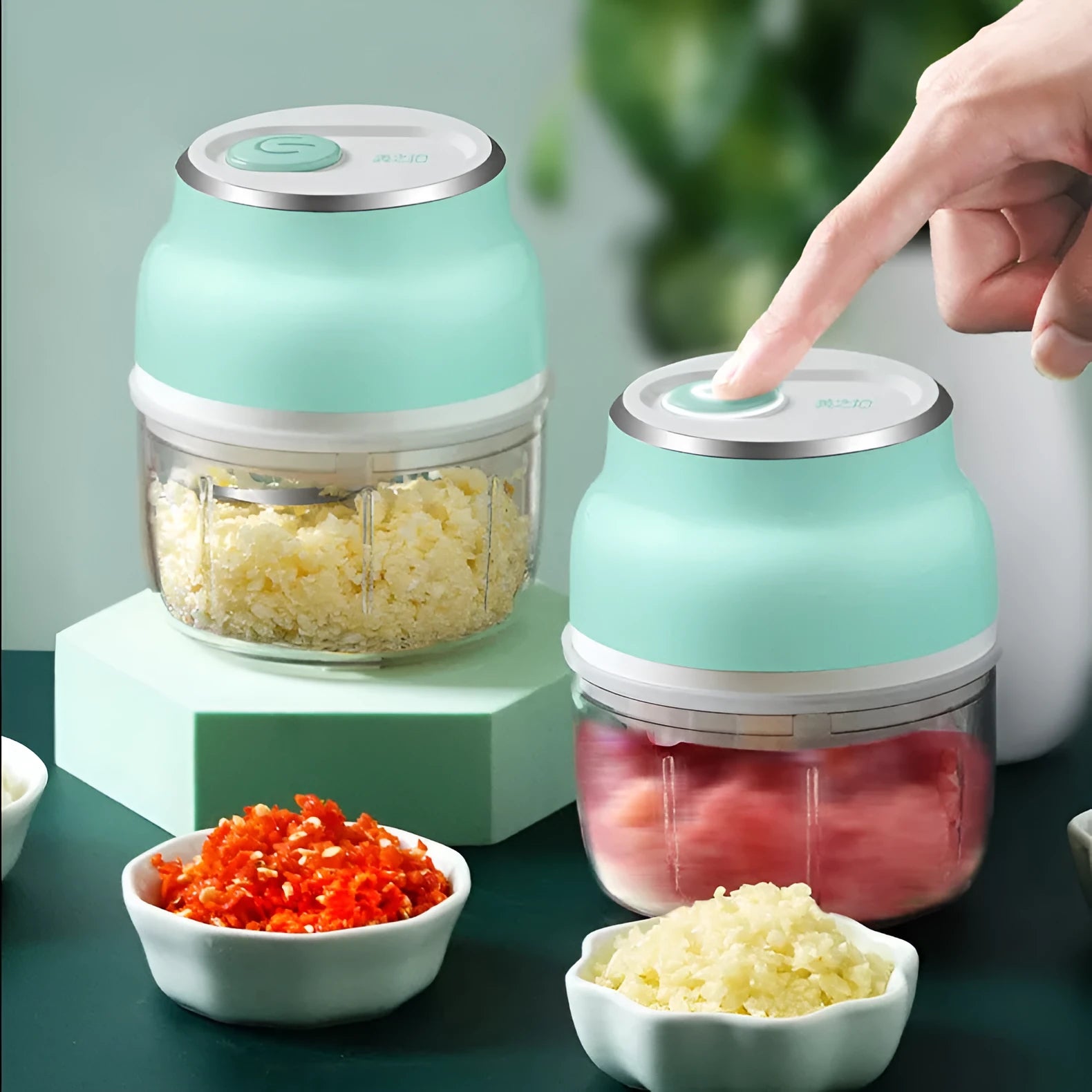 White portable electric mini food chopper with transparent cup and stainless steel blade on a kitchen counter.