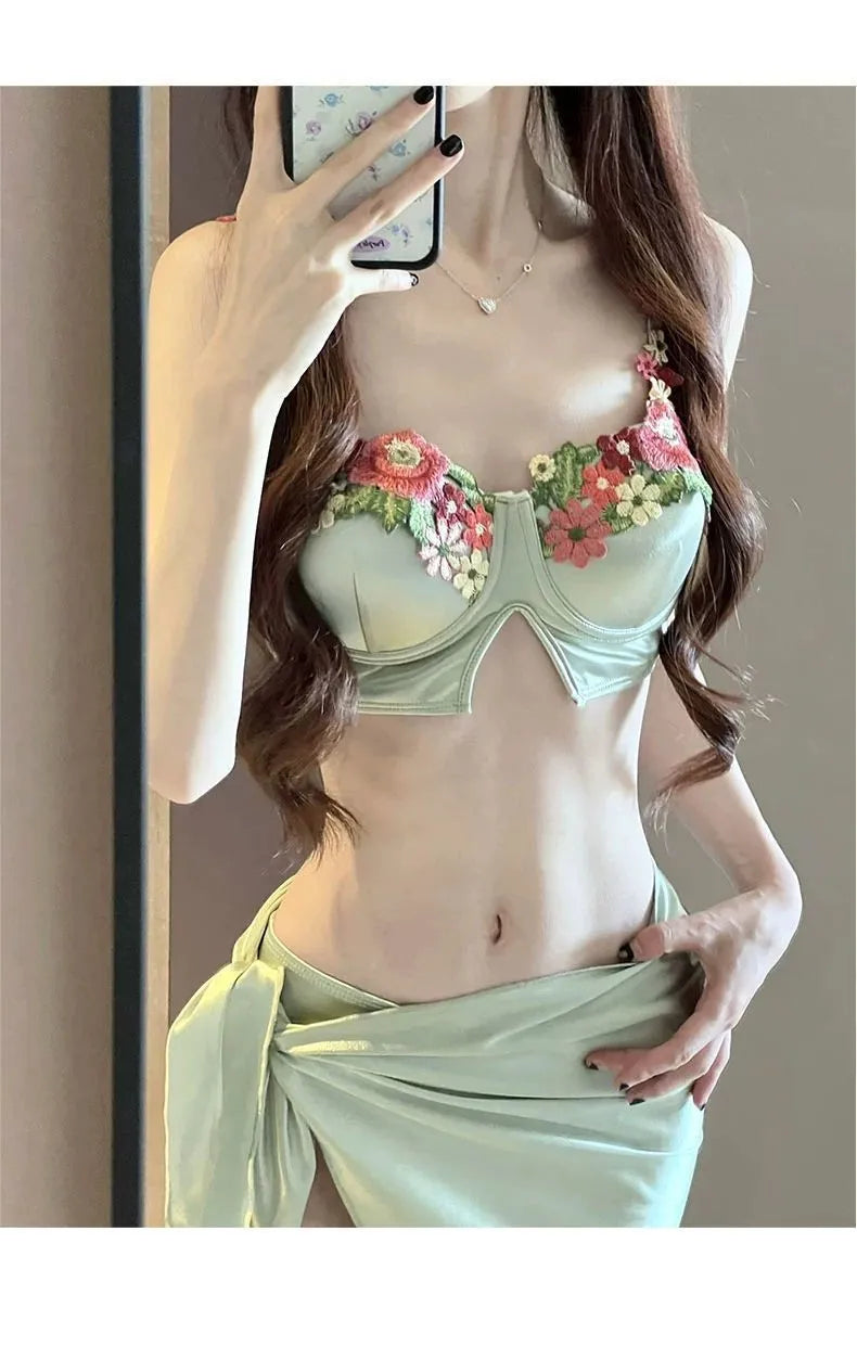 Green women's three-piece bikini swimsuit set with triangle top, briefs, and matching skirt